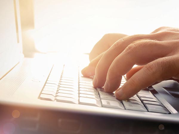 Hands typing on a laptop